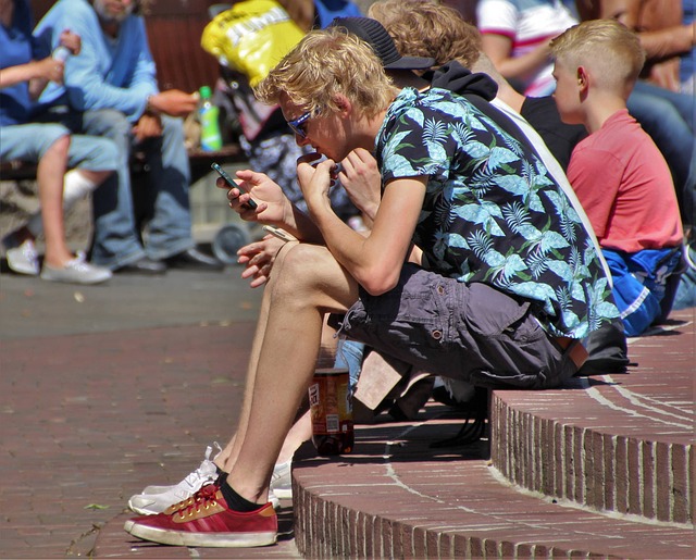 chlapci sedící na veřejném prostranství s telefonem